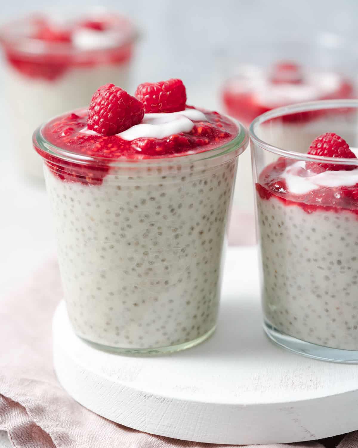 Side shot of a jar of chia pudding topped with mashed raspberries.