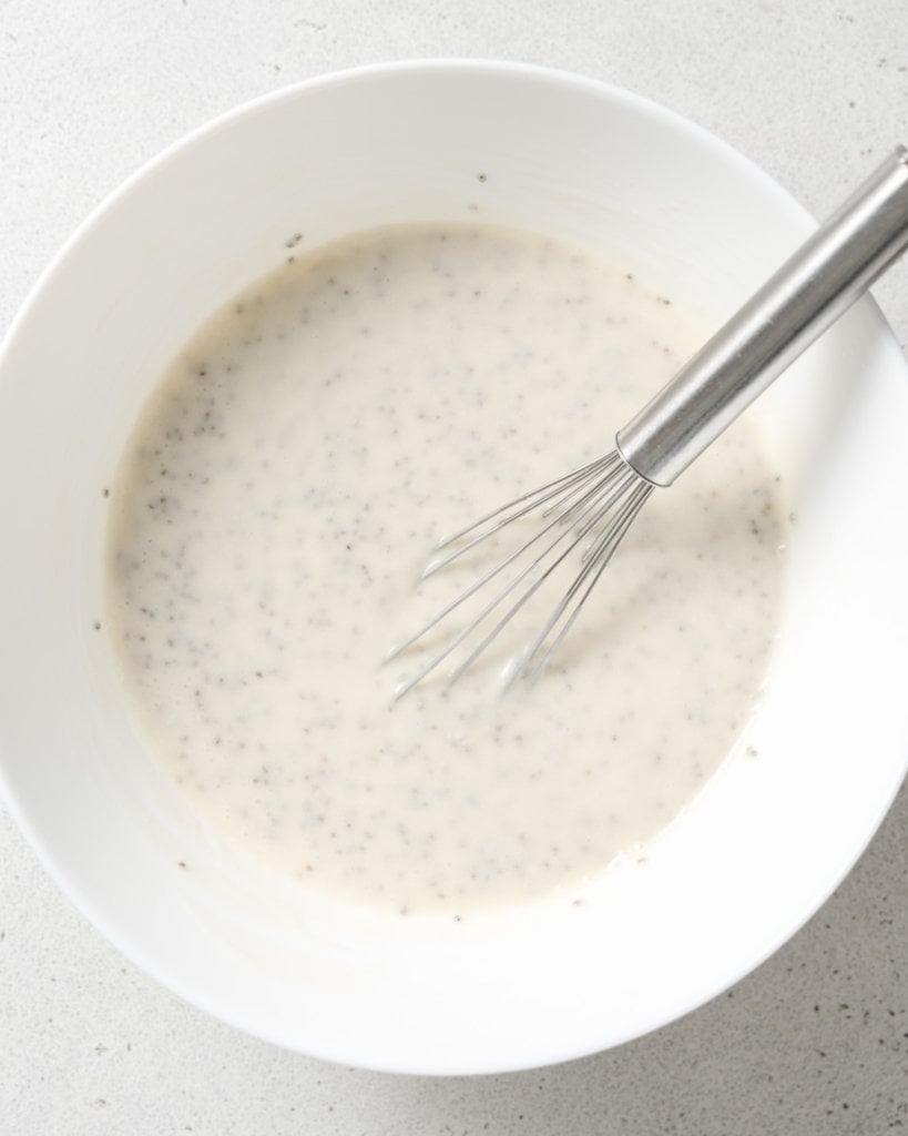 Using a whisk to stir chia seeds with yogurt and milk.