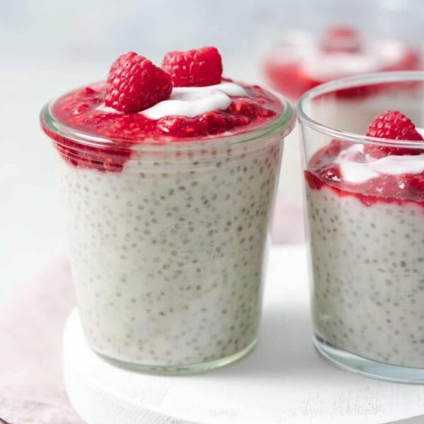 side shot of a jar of chia pudding topped with mashed raspberry