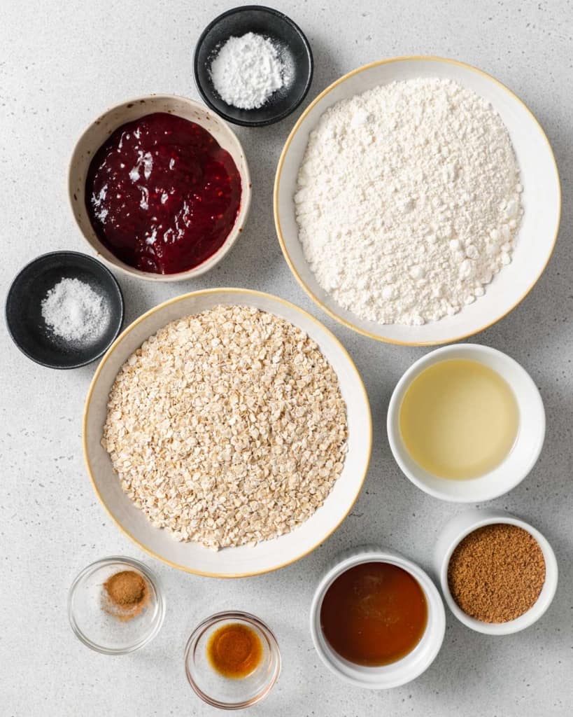Flour, instant oats, raspberry preserves, oil and cinnamon divided into small bowls.