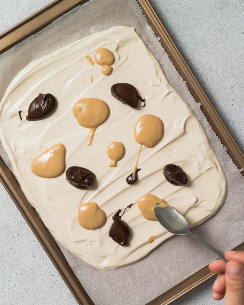 Adding spoonfuls of peanut butter and melted chocolate.