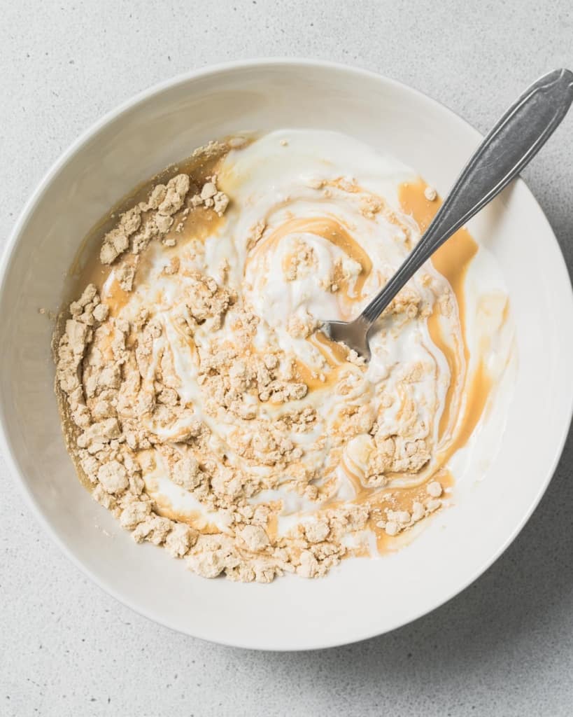 Stirring protein powder with yogurt and peanut butter.