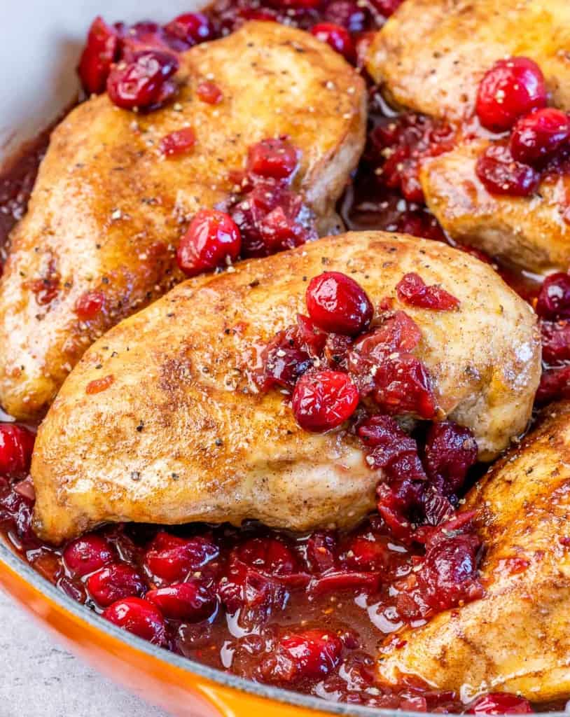 Chicken breasts cooked in a pan with cranberry sauce.