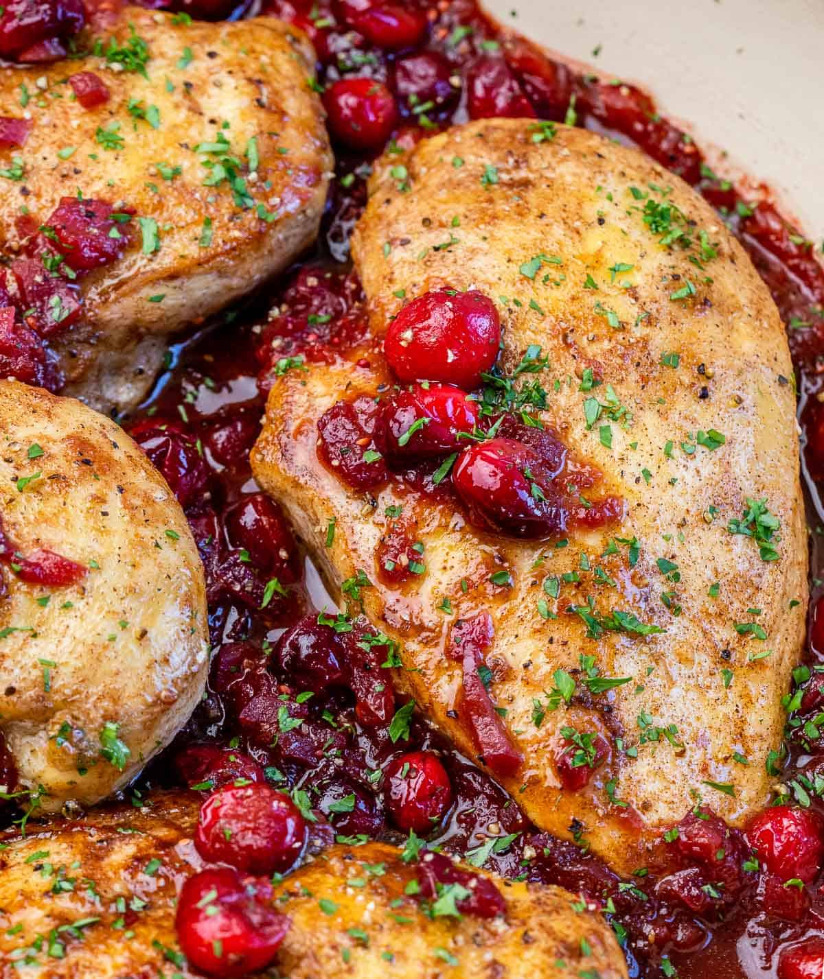 Cranberry roasted chicken topped with cranberries and fresh parsley.