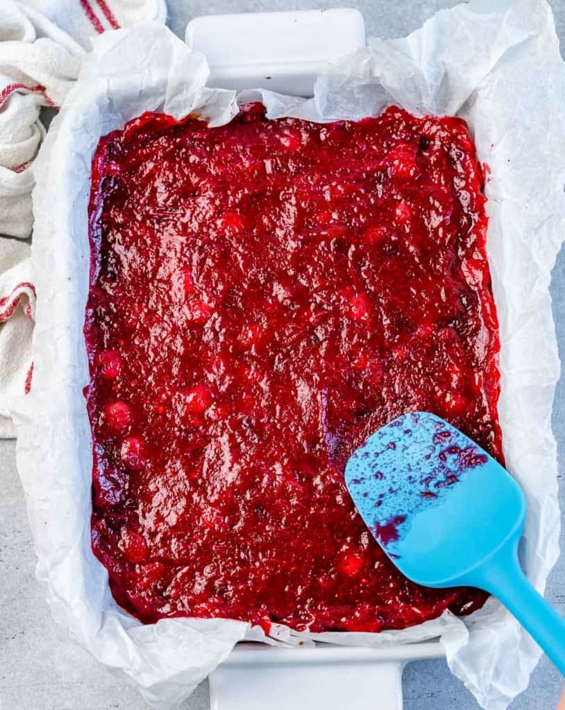 Spreading cranberry sauce over a cookie crust.