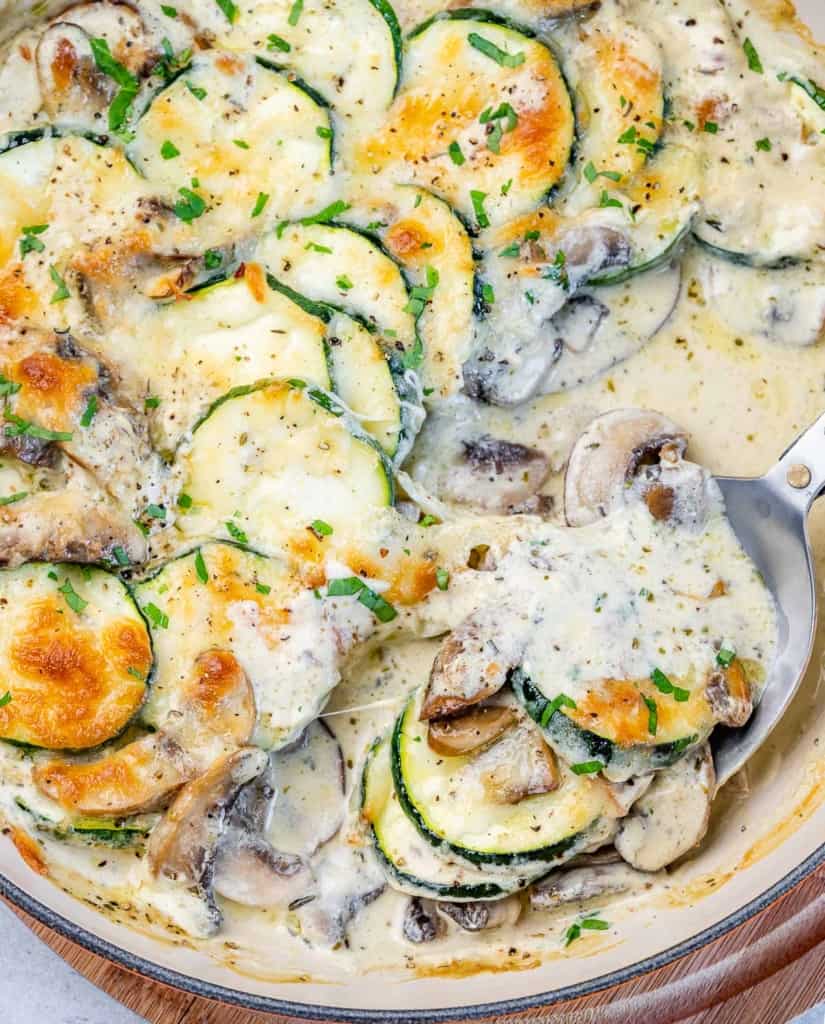 top view of spoon in a dish with zucchini and mushrooms in a creamy sauce 