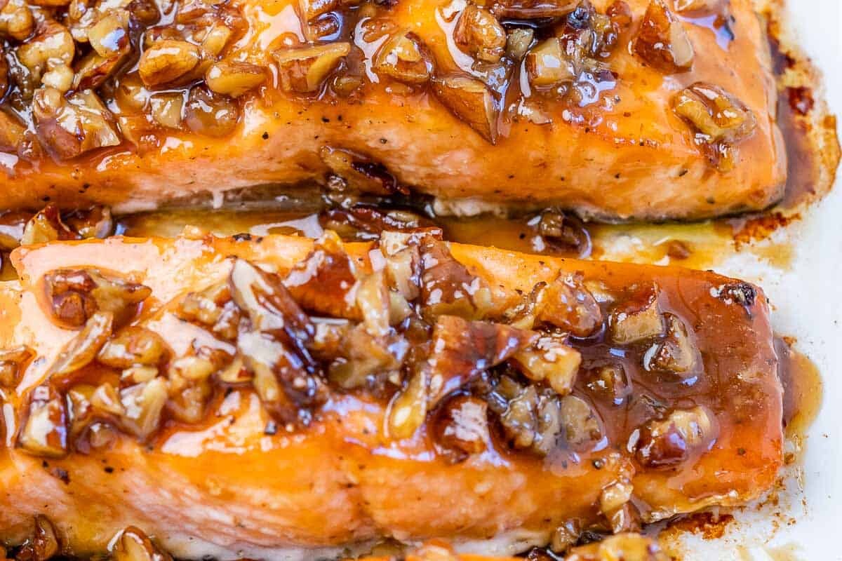 Filets of salmon topped with a maple pecan glaze in a white dish.