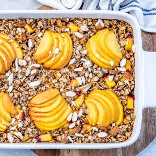 baked oatmeal in a white baking dish with slices of peach on top