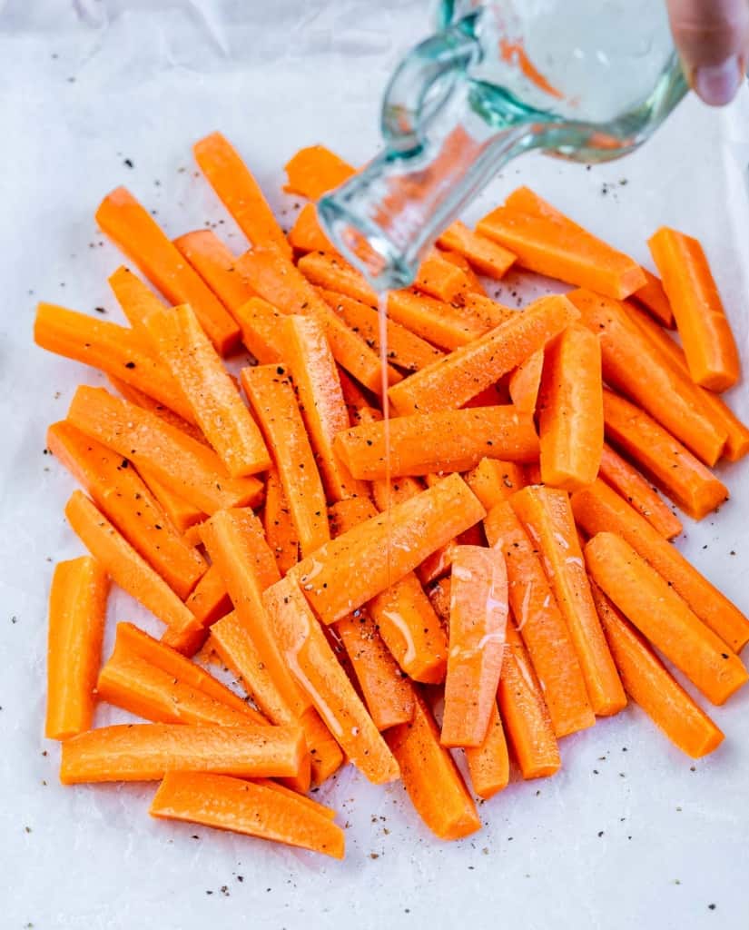 Drizzling carrots with olive oil.