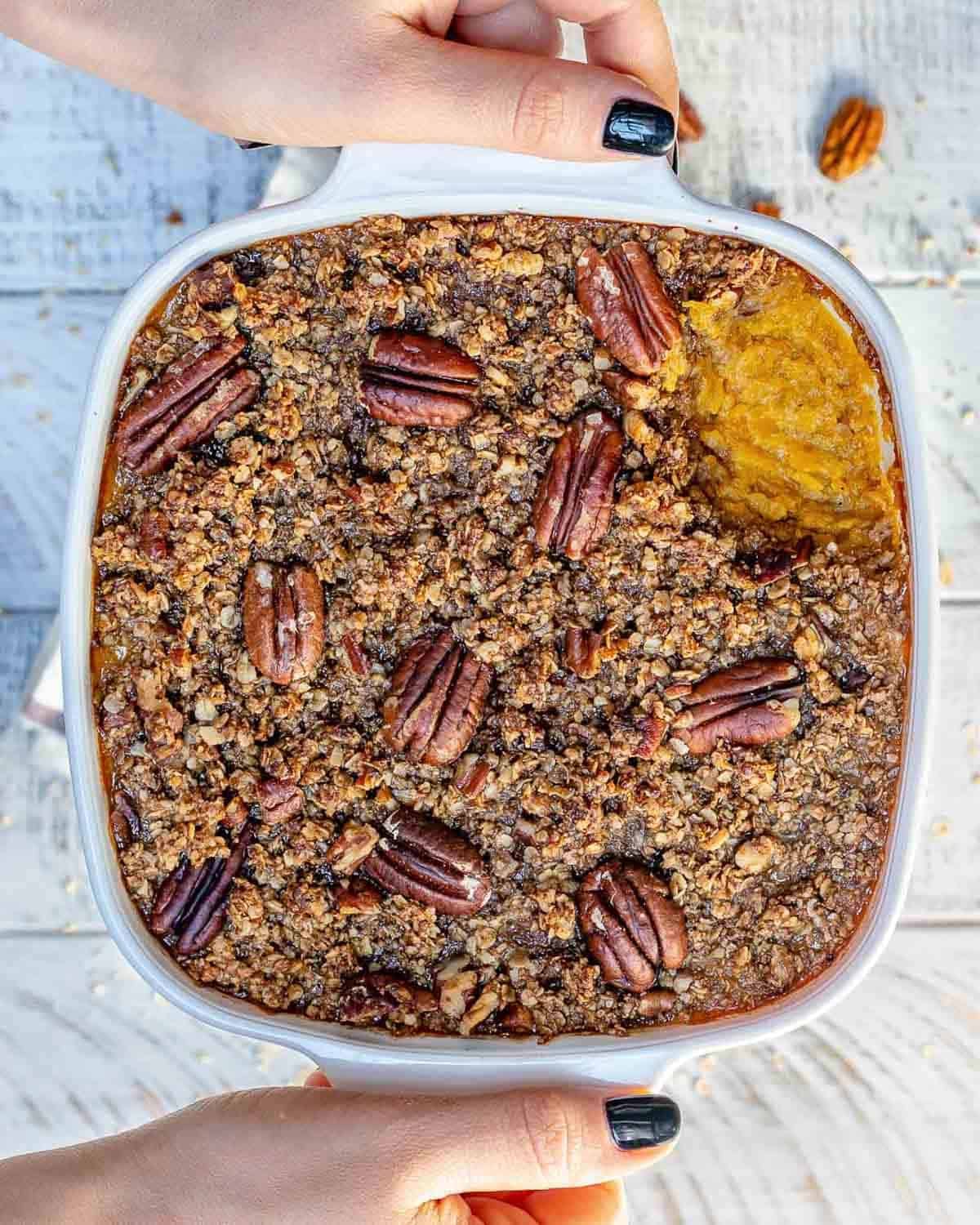 hand holding a dish with butternut squash casserole.