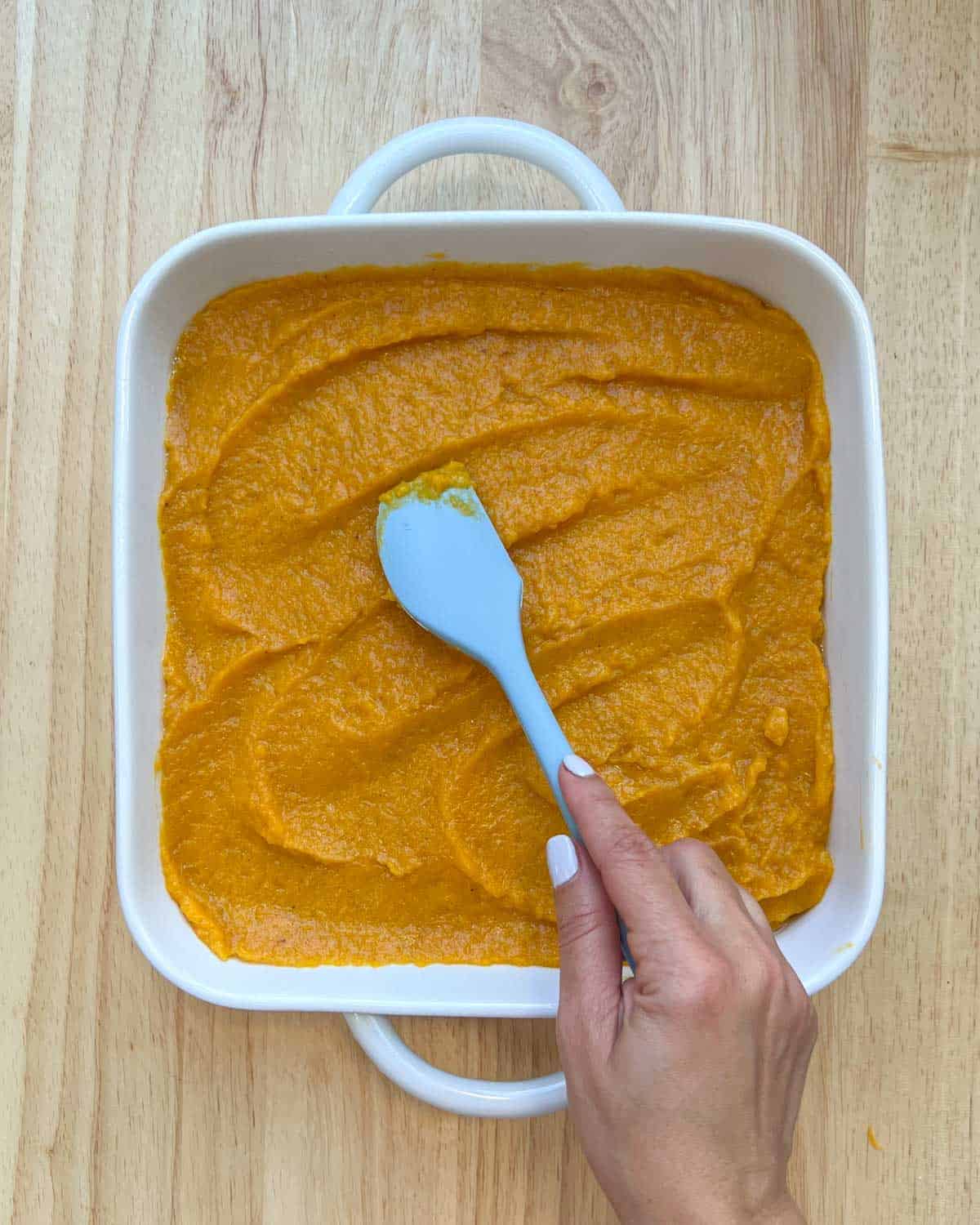 Butternut squash puree base added to a baking dish and spread out evenly with a spatula.