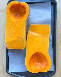 Seasoning butternut squash to be roasted.