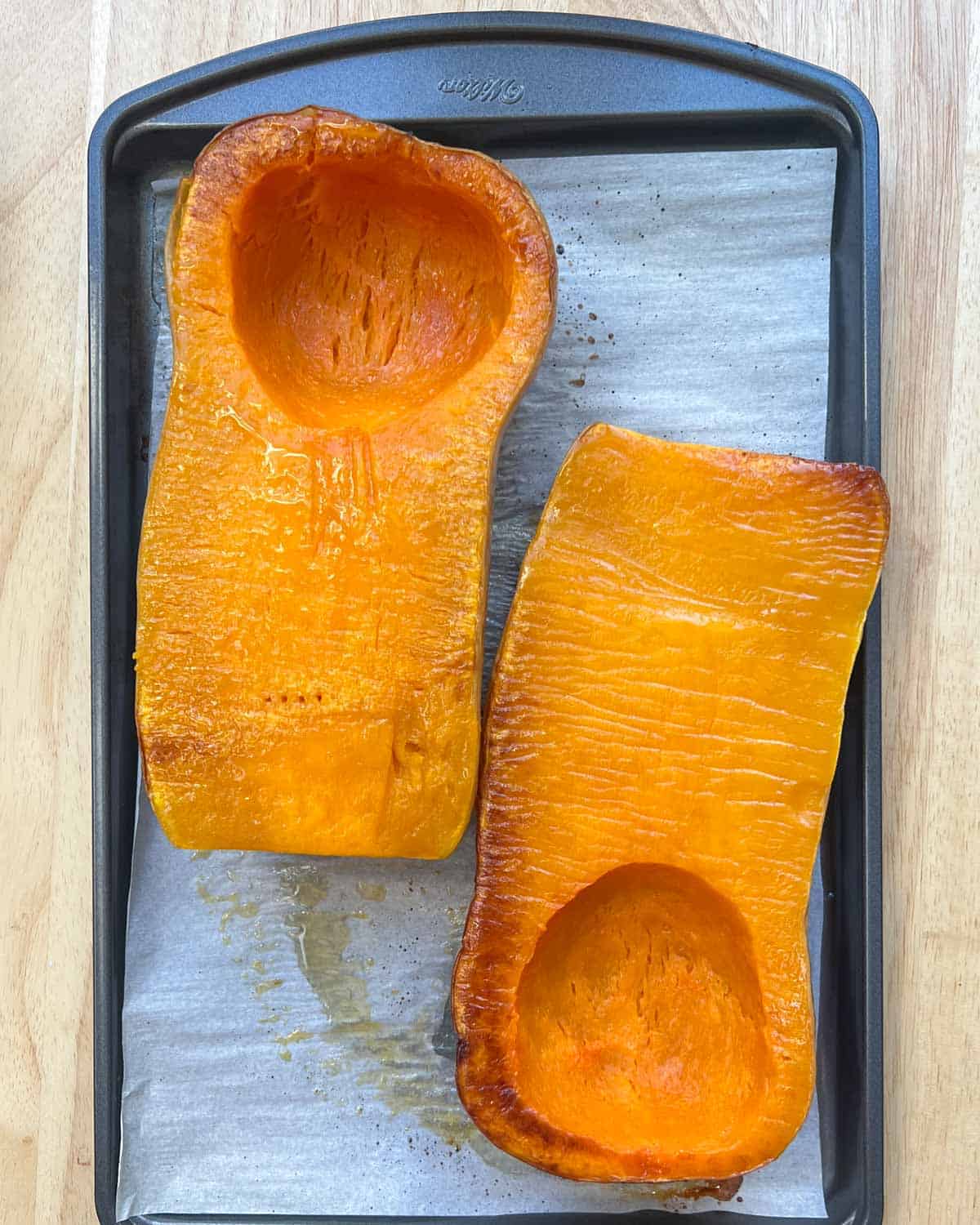 roasted butternut squash halves on a sheet pan.