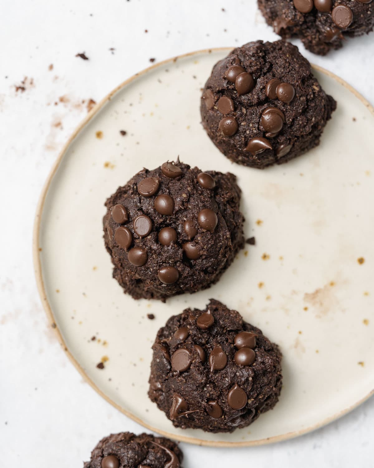 Chocolate cookies with chocolate chips on a white plate.