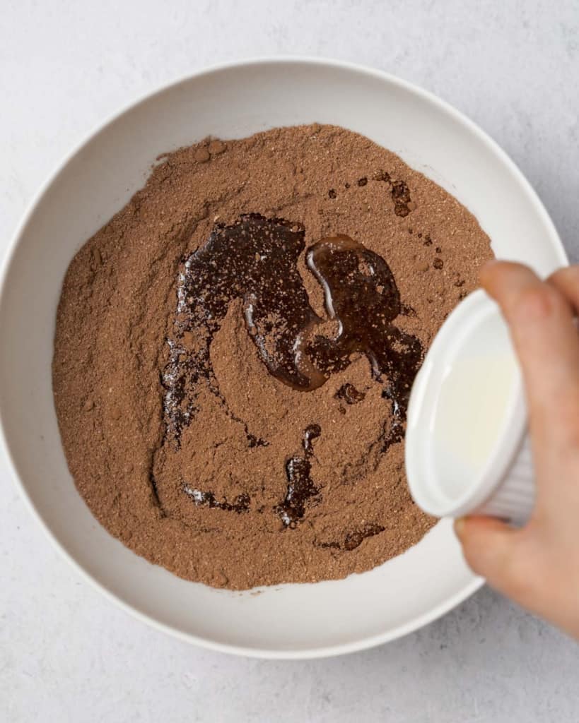 Adding oil to cocoa powder mixture in a large bowl.