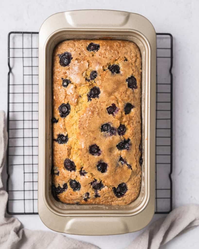 baked blueberry bread in pan over a wire wrack