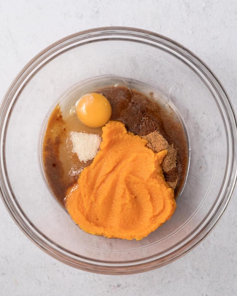 pumpkin puree added with egg and sugar in a round clear bowl
