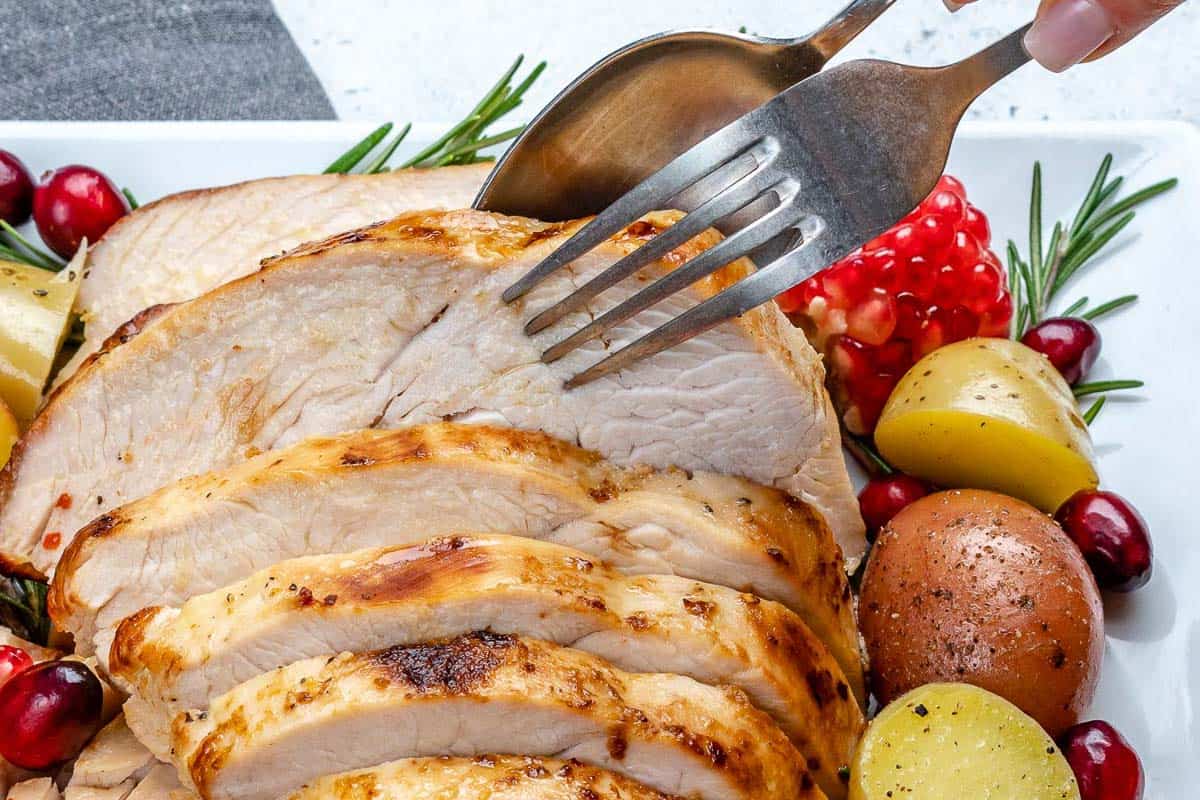 fork removing a slice of turkey breast from the dish.
