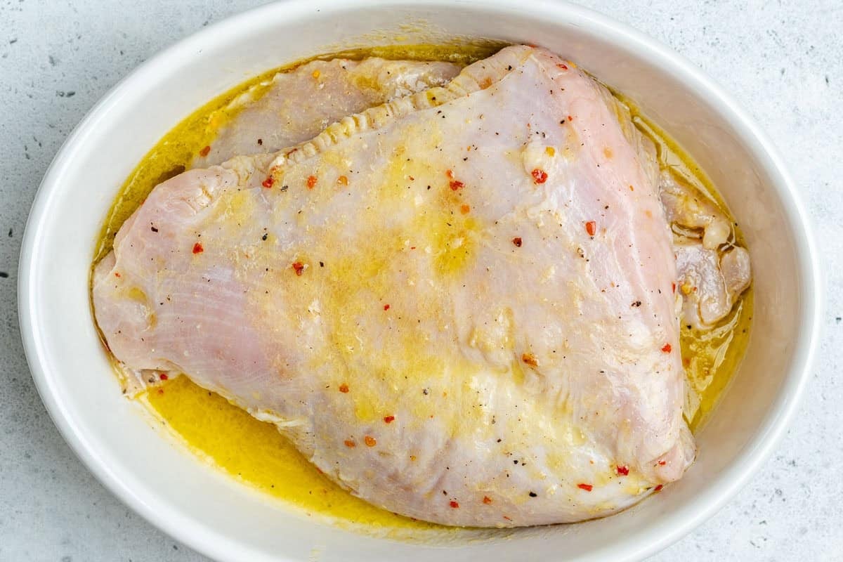 Marinated boneless turkey breast in a dish.