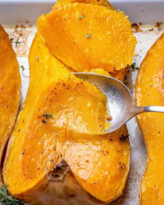 Spoon scooping butternut squash that's roasted in a pan.
