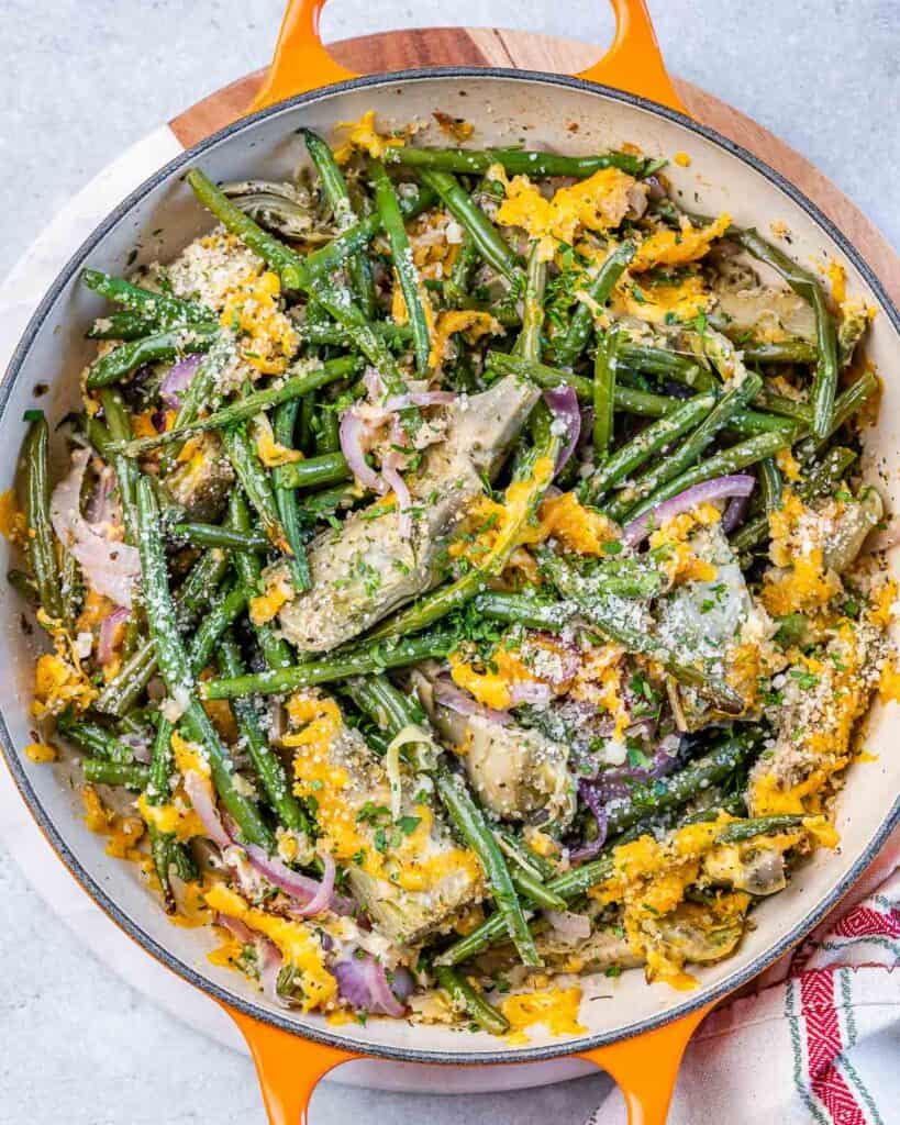 top view casserole of artichoke and green beans topped with shredded cheese 