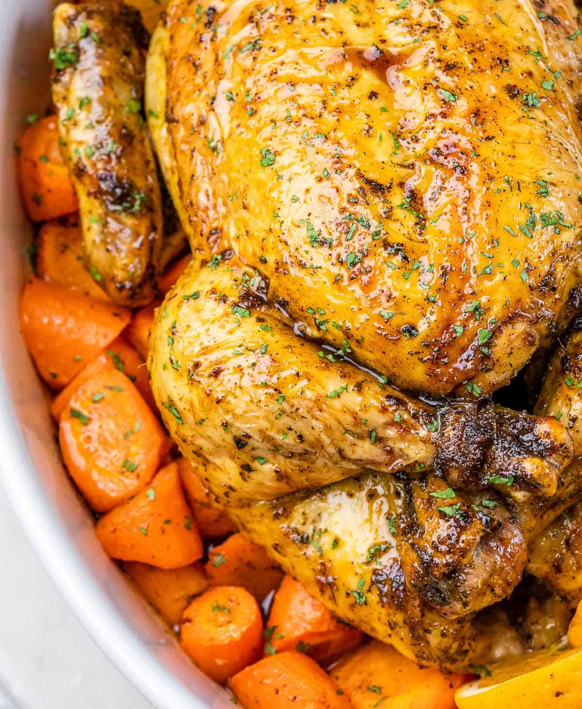 Close-up view of a whole chicken over carrots.