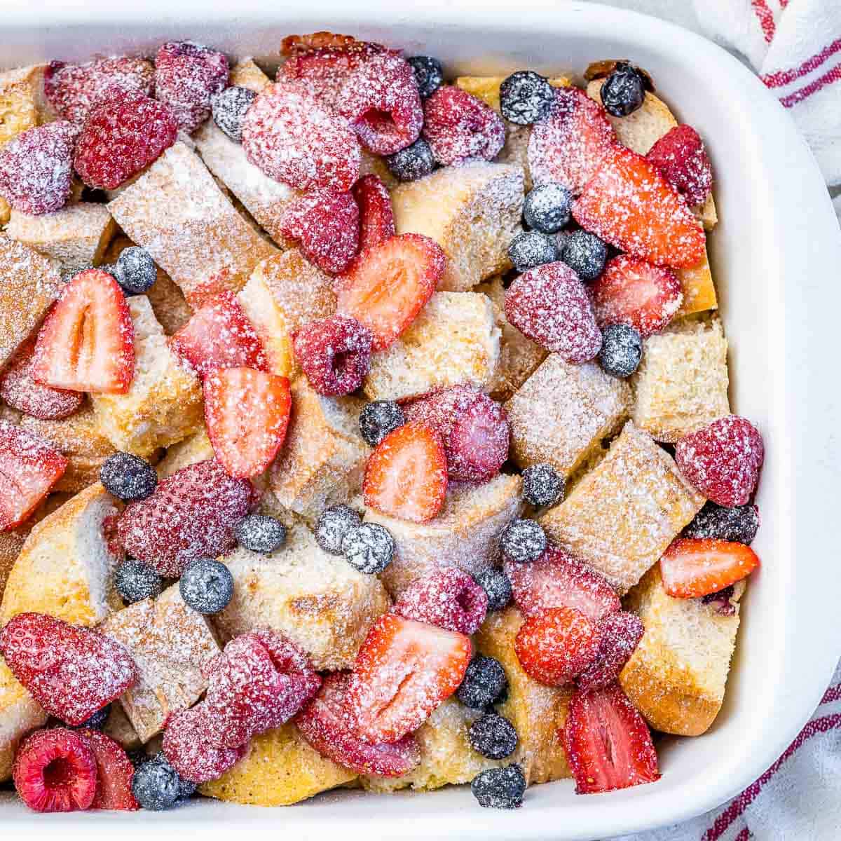 top view of a white dish with french toast casserole topped with fresh berries