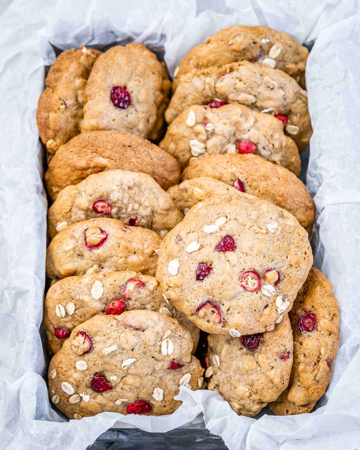 Cranberry oatmeal cookies packaged in a container lined with parchment.