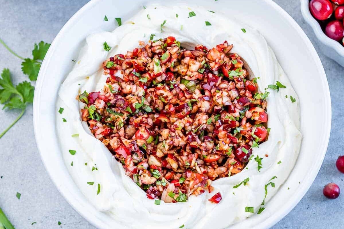 Cranberry salsa served over whipped cream cheese in a white bowl.