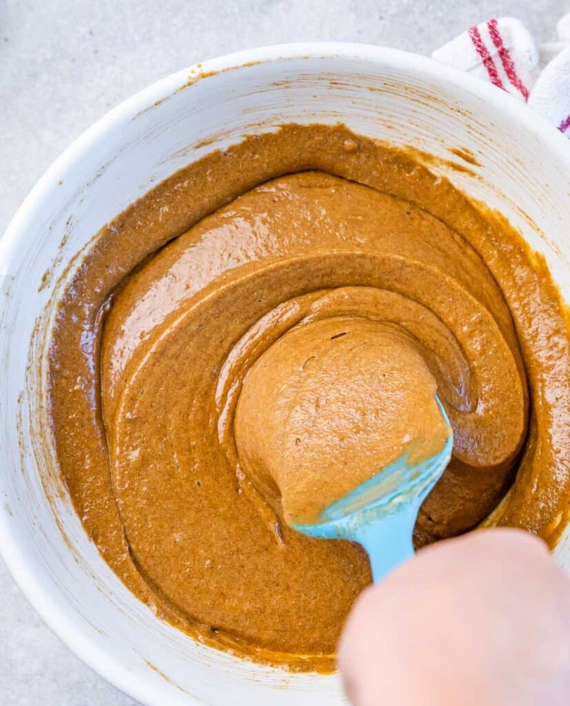 Stirring a brown batter with a spatula. 
