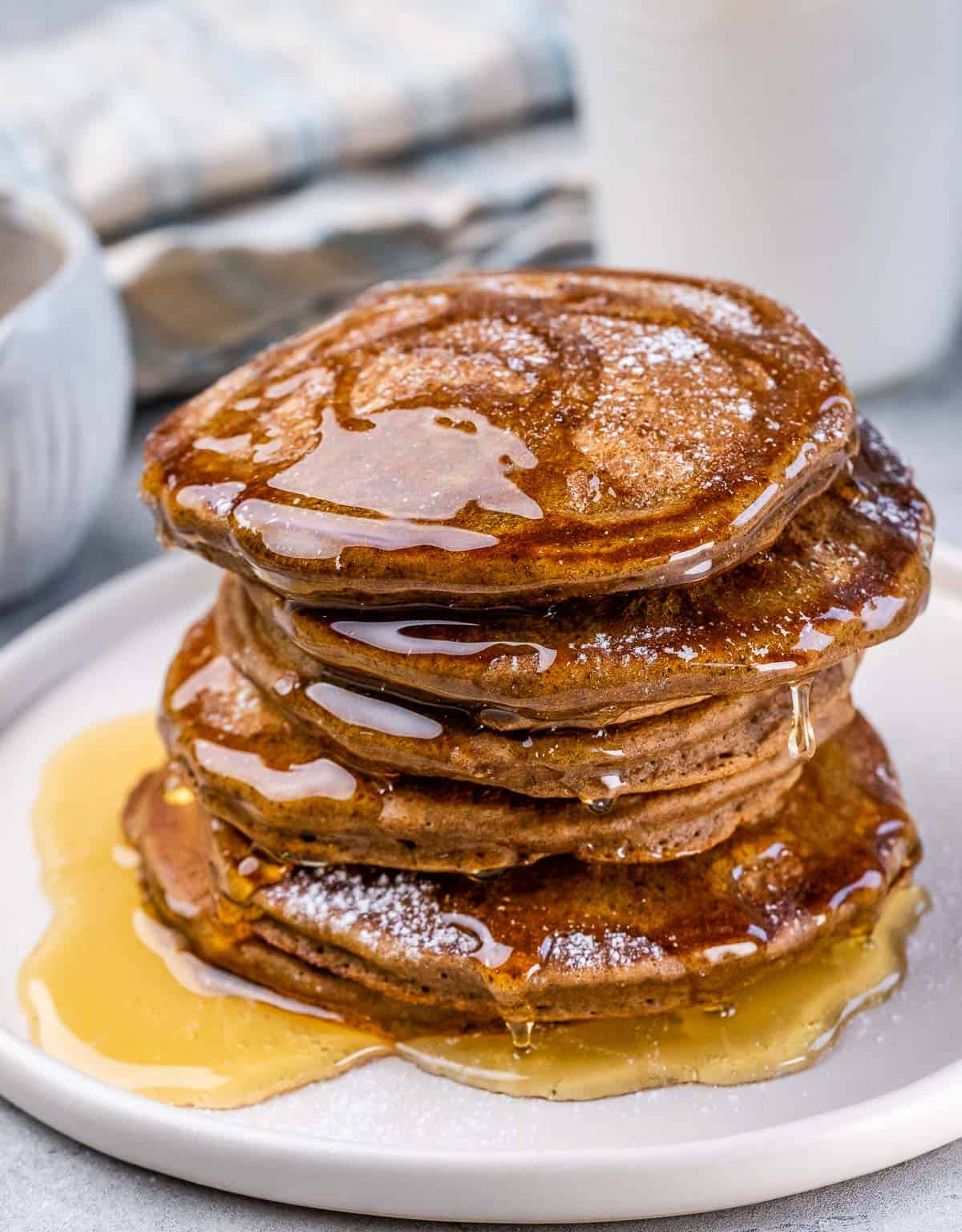 Stack of gingerbread pancakes drizzled with honey on a plate. 