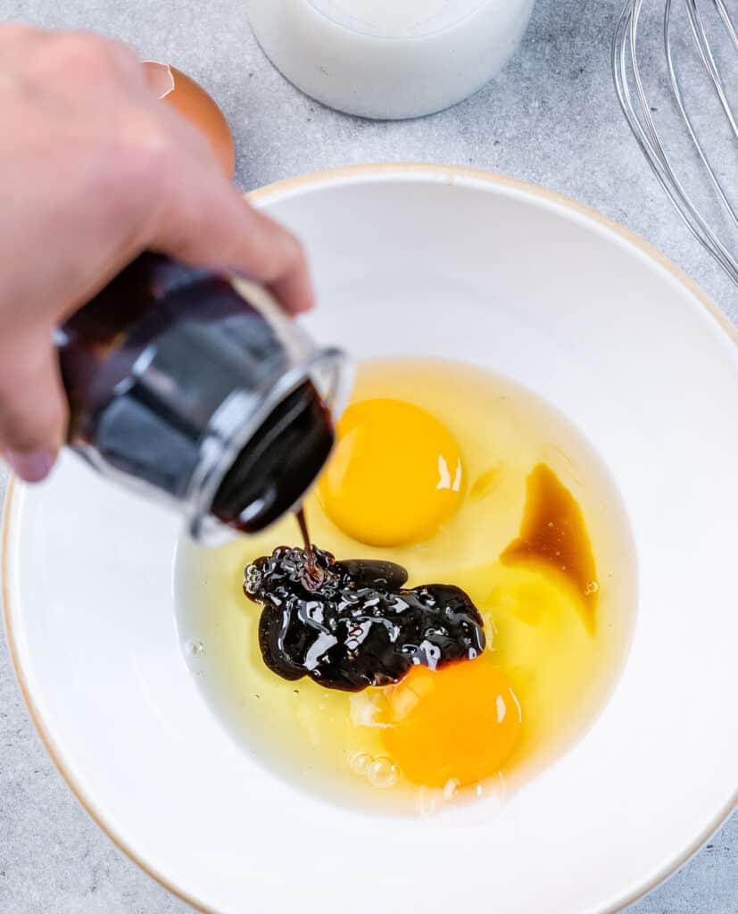 Adding molasses to eggs and vanilla in a bowl.