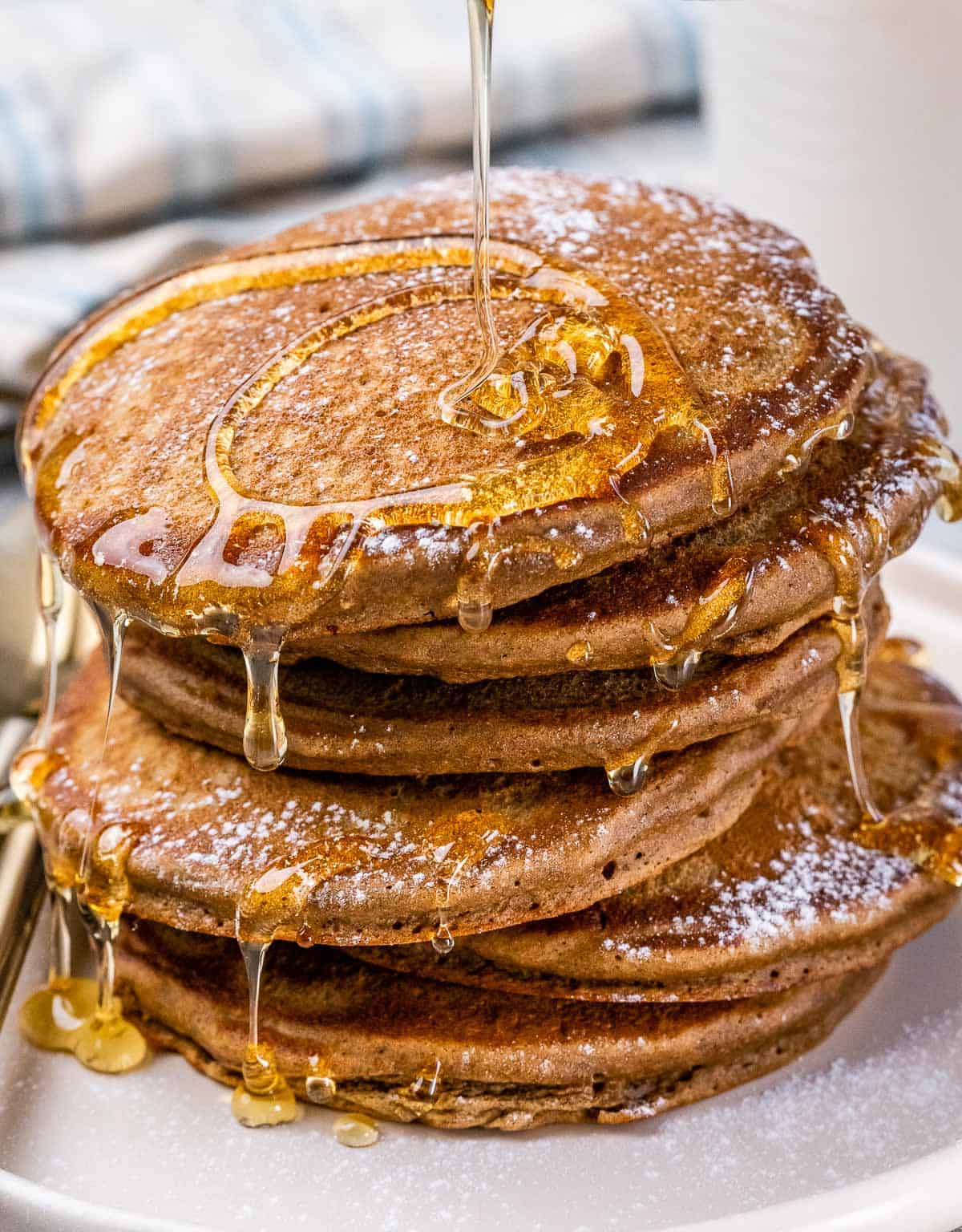 Closeup view of a stack of pancakes drizzled in maple syrup.