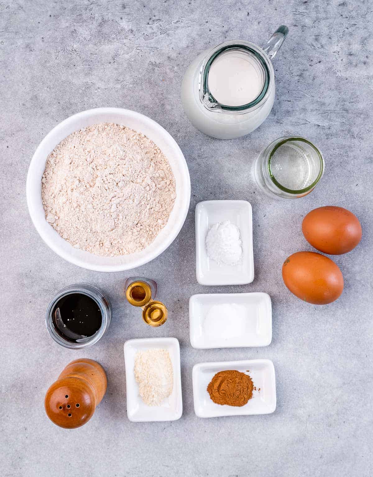 Flour in a bowl near eggs spices, oil and milk.