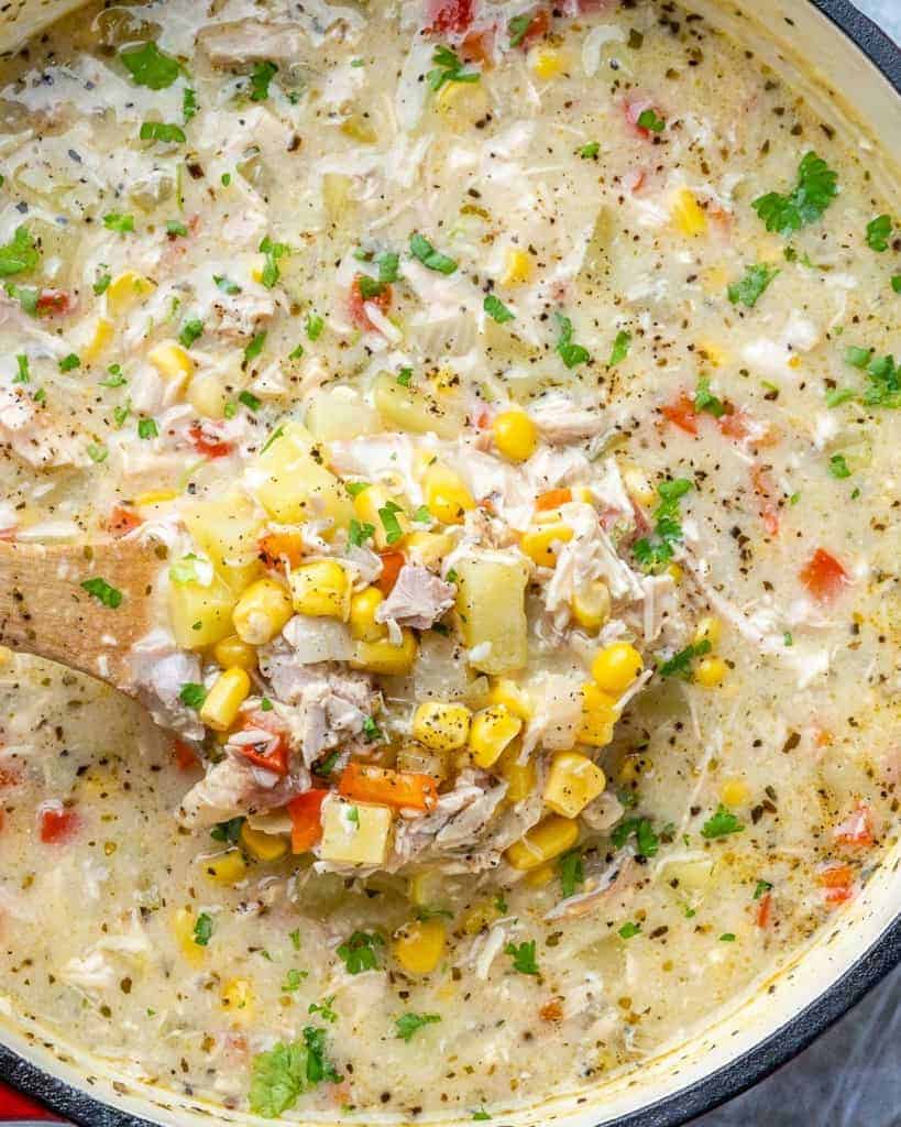 Close-up view of corn chowder soup in a pot with a spoonful.