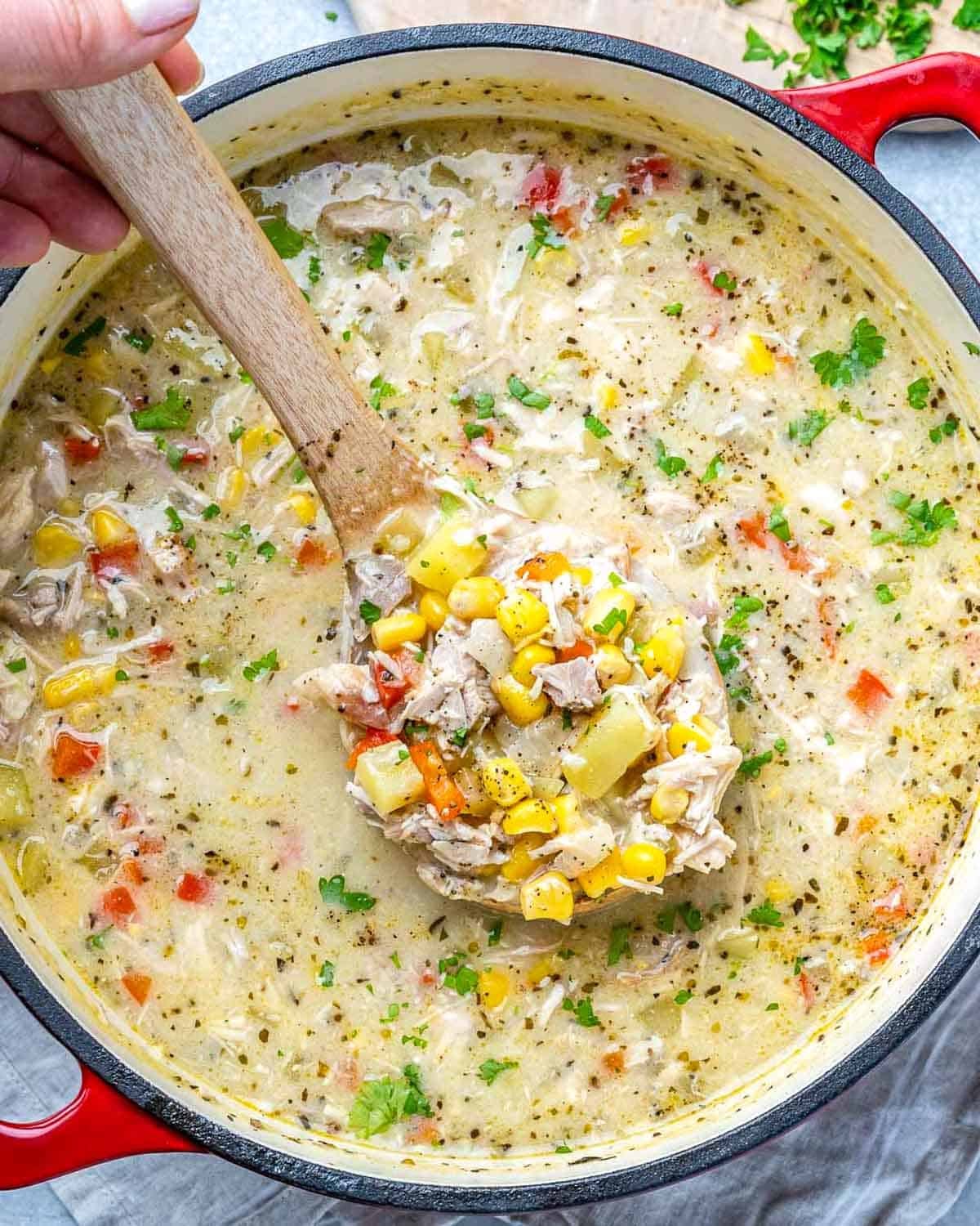 a pot of chicken and corn soup with a poon in the pot. 