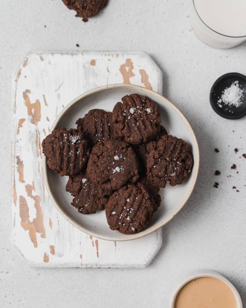 Chocolate cookies on a round white plate over a cutting board
