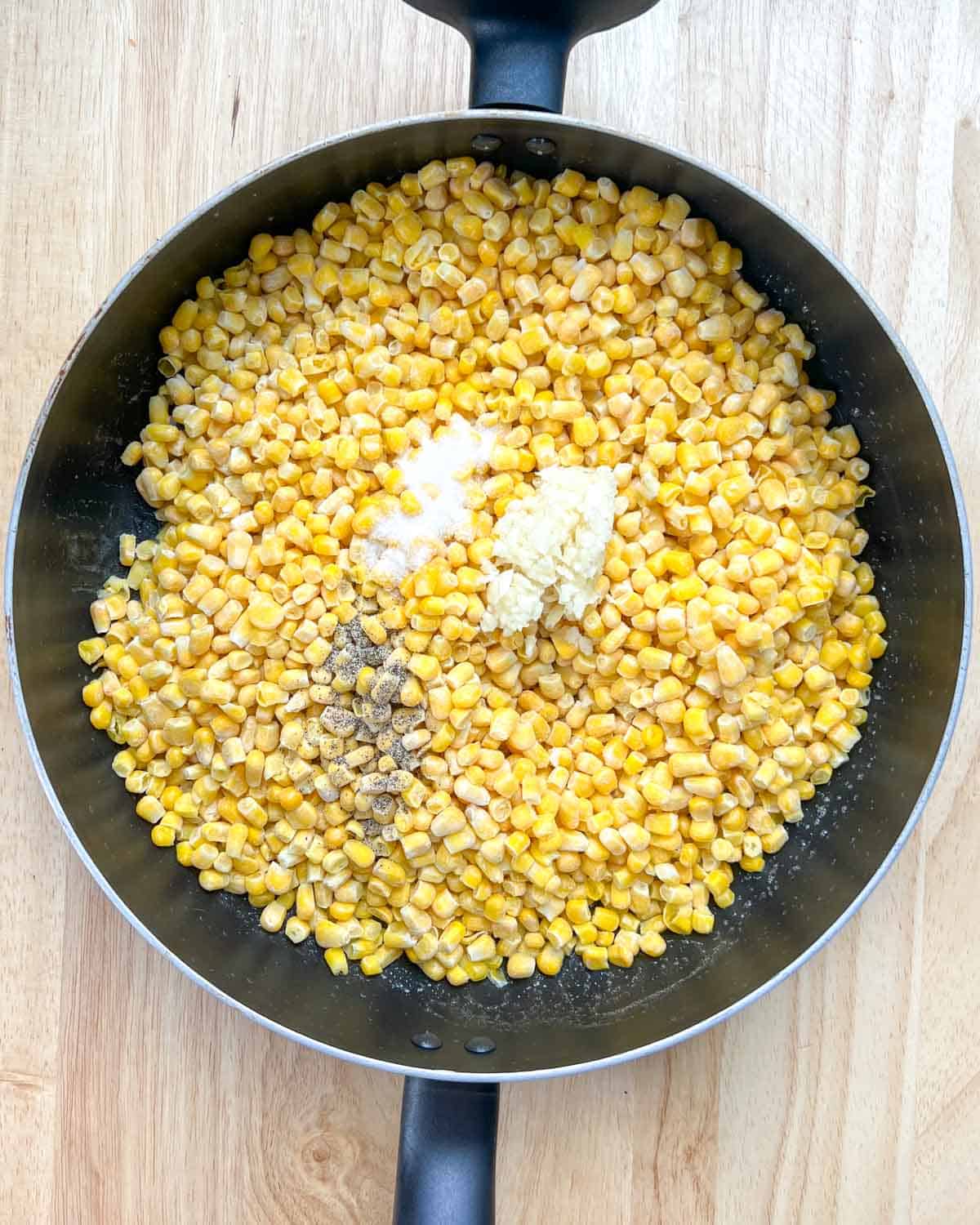Corn was added to the pan, and salt, pepper, and minced garlic were added to it.