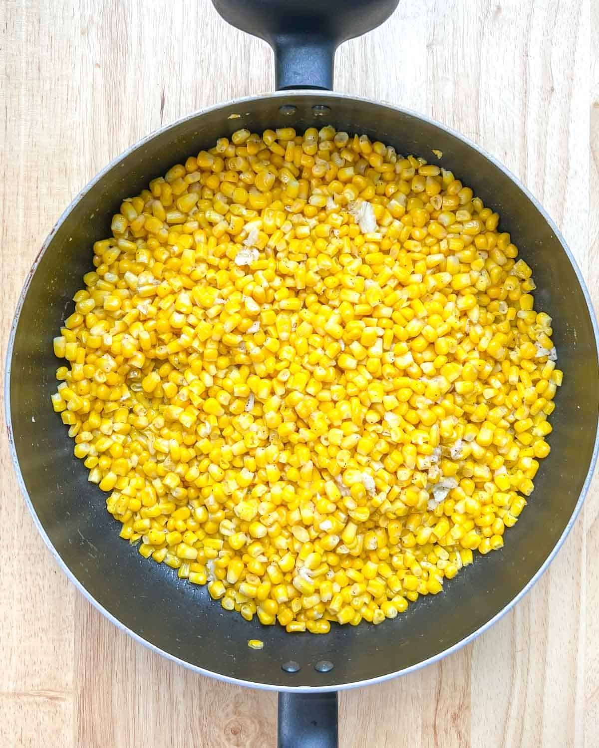 Corn and garlic are seared in a pan.