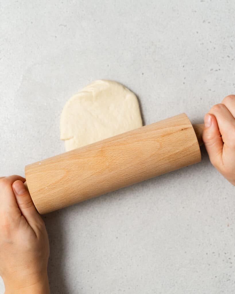Rolling a section of dough with a rolling pin.