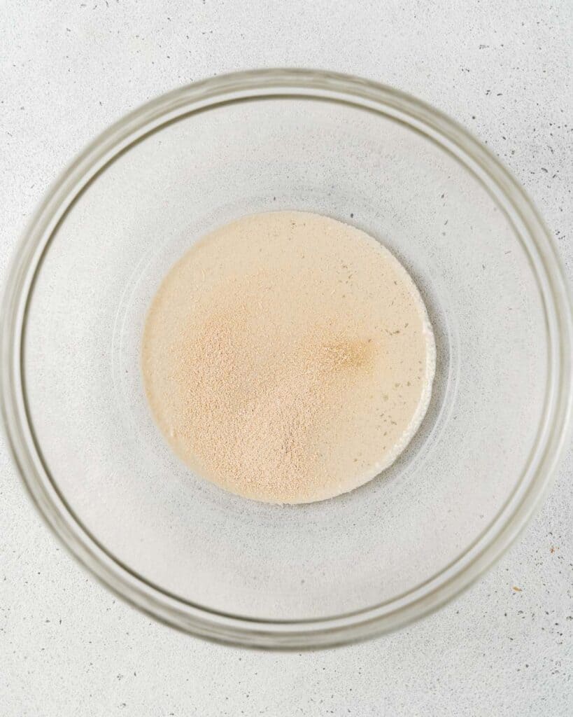 Mixing yeast with warm water in a bowl.