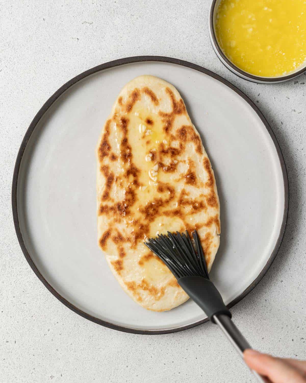 Brushing naan with melted butter.
