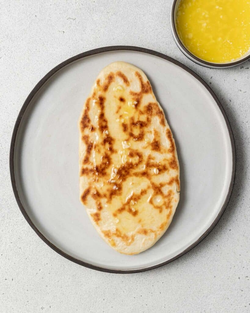 shot of s single naan bread on a plate before adding any garlic butter on it 