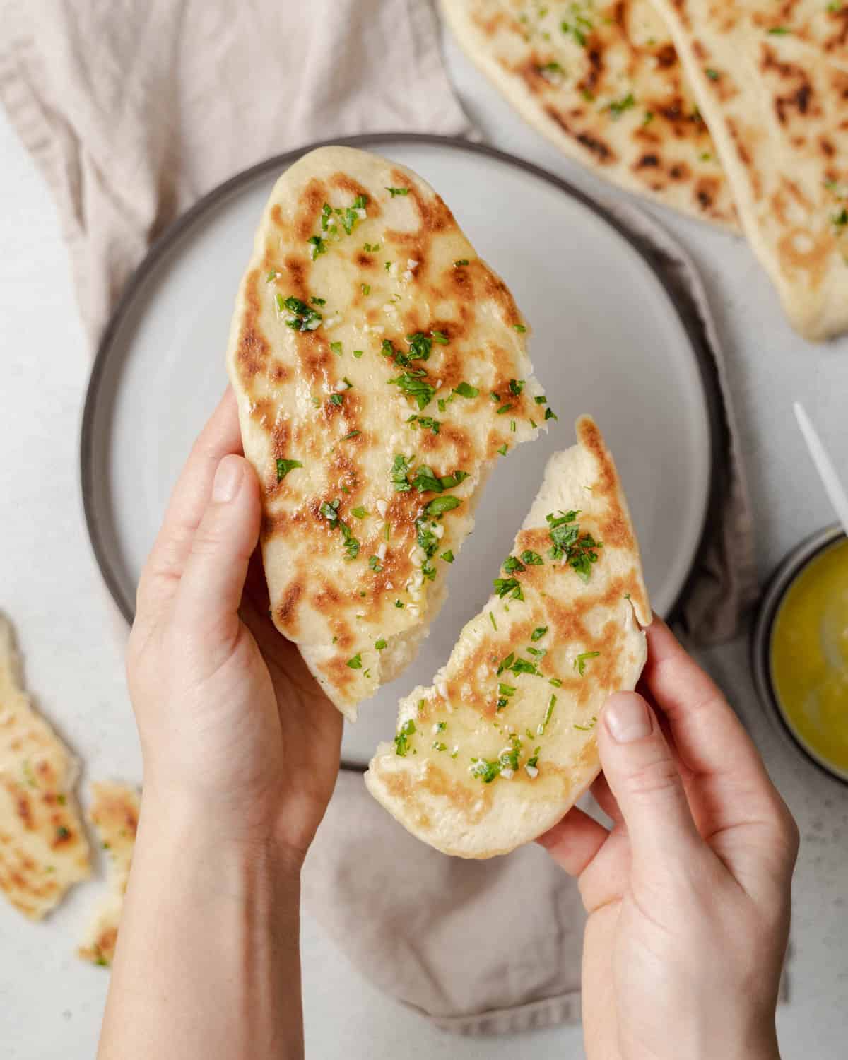Hand holding two halves of naan bread.