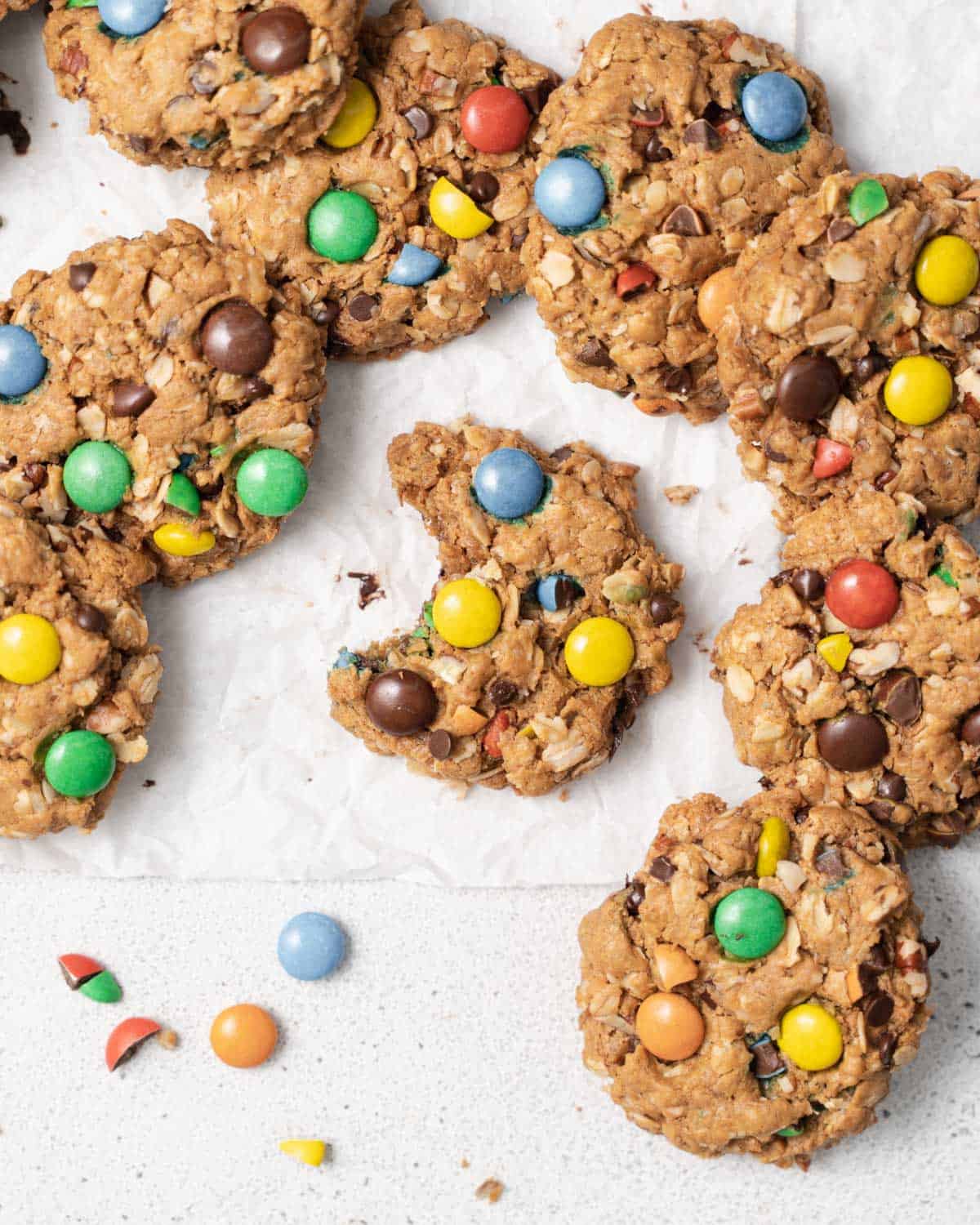 Oatmeal cookies with M&M's and chocolate chips on parchment paper.