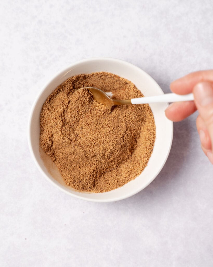 Mixing cinnamon and sugar in a small white bowl.