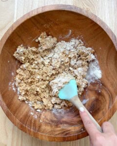 using a spatula mixing the oats, peanut butter, honey, and protein powder in a bowl.