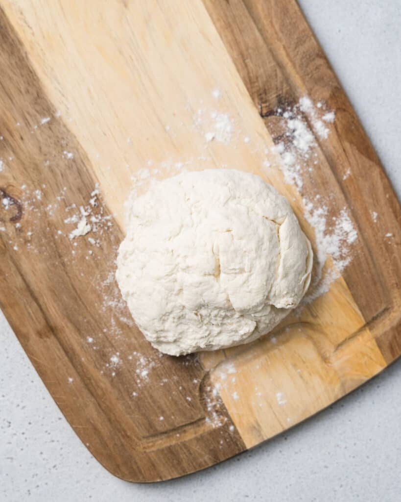 dough placed on a wooden cutting board