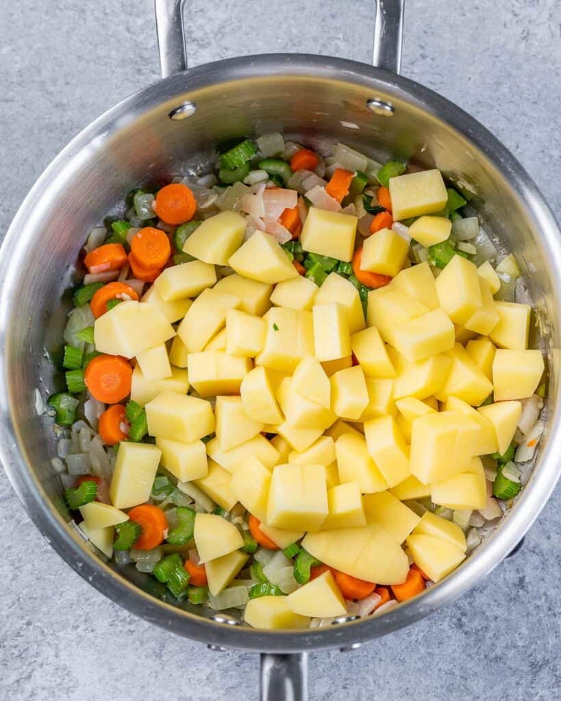 Adding vegetables to a soup pot.