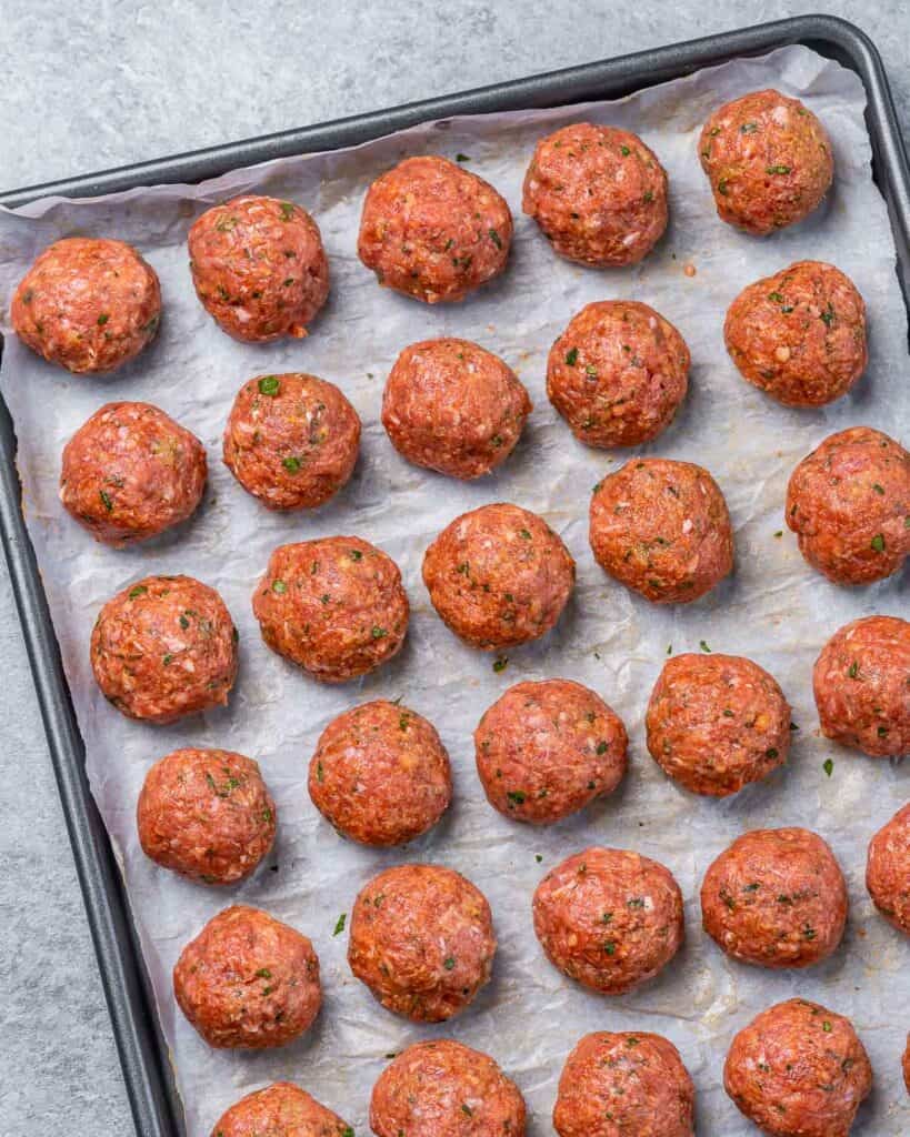 Raw meatballs on a baking sheet.